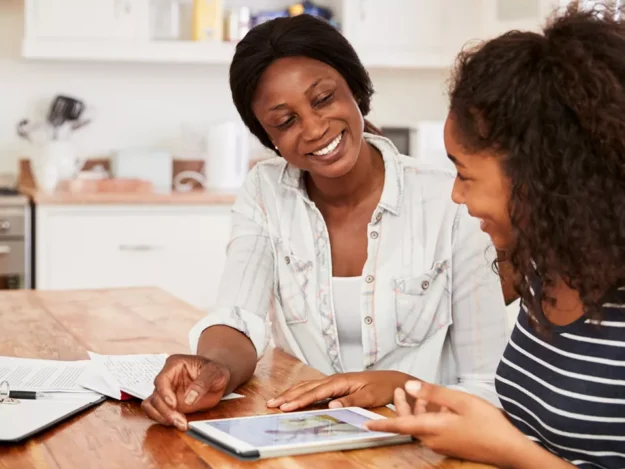 Adult And Teen Sat At The Kitchen Table