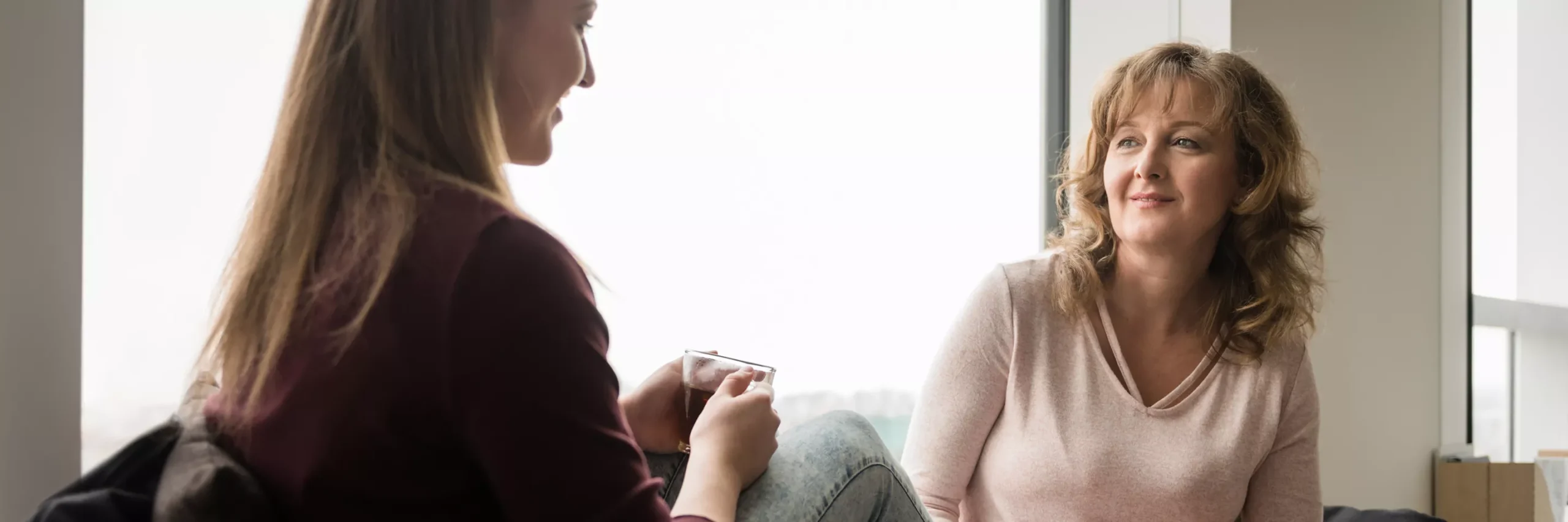 Adult Sat Talking To A Young Person Whilst Drinking Tea