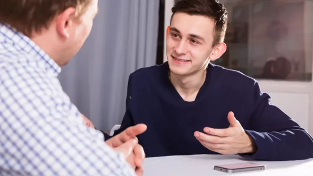 Young person having a discussion with adult at the table