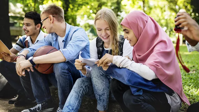 Group of diverse young people from different cultural backgrounds sat outside together