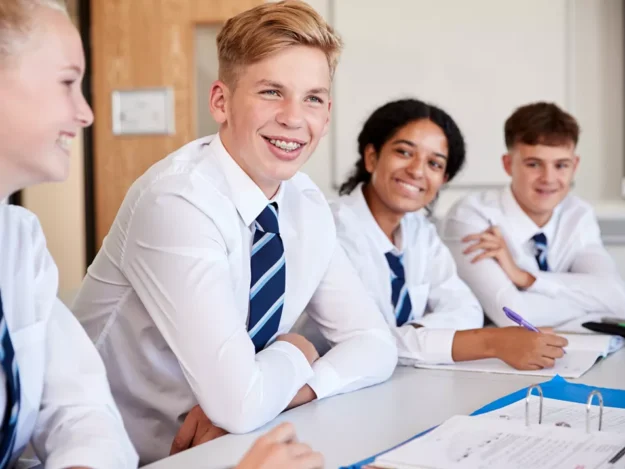 Row of school students in uniform sitting at their desks in the classroom