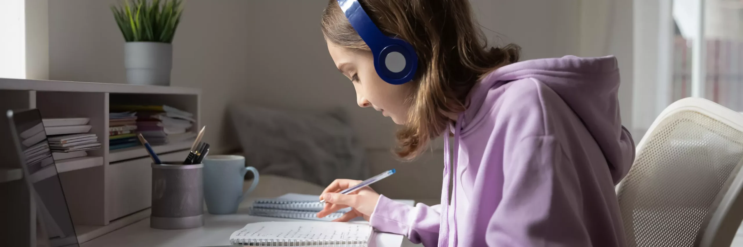 Teenage Girl With Headphones On, Doing Work On Her Laptop