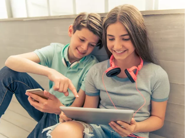 Two Young People Using A Tablet And Mobile Phone Together