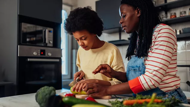 Young Person And Adult Chopping Vegetables